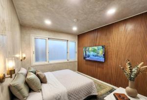 a bedroom with a bed and a tv on a wall at Billy Hostel in Busan