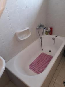 a bath tub with a pink mat in a bathroom at Real Apartment Αληθινή Διαμονή in Diakopto +10 photos