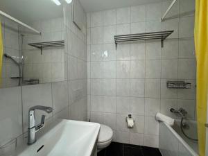 a bathroom with a sink and a toilet and a tub at Eiger Residence 1 in Wengen +16 photos