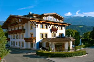 a large white building on a street with mountains at Gartenhotel Maria Theresia in Hall in Tirol