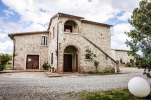 an old stone house with a large building at Villa Acquaviva Wine Resort in Montemerano