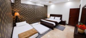 a hotel room with two beds and a lamp at 430 Elite Reside in Islamabad