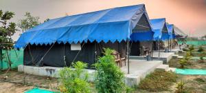 a row of tents with blue tarp at Bhitarkania Riverside Eco Resorts in Righāgarh