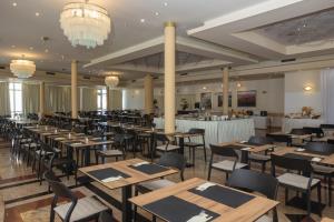 a dining room with tables and chairs and chandeliers at Hotel Punta in Vodice