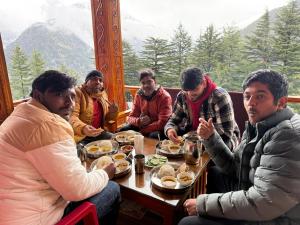 a group of men sitting around a table eating food at Harshil View Home Stay in Harsil
