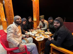 a group of men sitting around a table eating food at Harshil View Home Stay in Harsil +31 photos