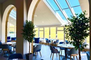 a dining room with tables and chairs and windows at Skipton Hotel in Skipton