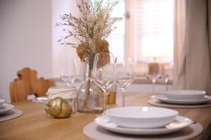 a wooden table with wine glasses and plates on it at Ferienwohnung Oswald mit Garten im EG in Kochel