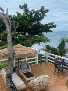 a patio with chairs and an umbrella and the ocean at Villa El Marie in Bacnotan