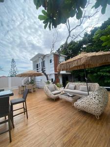 a patio with couches and umbrellas on a wooden floor at Villa El Marie in Bacnotan +10 photos