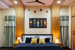 a bedroom with a bed with blue sheets and yellow pillows at Prana pulse villa stay gokulam in Mysore