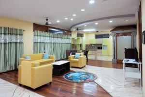 a living room with yellow chairs and a tv at Prana pulse villa stay gokulam in Mysore