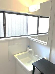a bathroom with a sink and two windows at The Village House 1 in Hadano