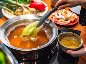 a person stirring a pot of soup with a spoon at LACER SUITES KAMAKURA -formerly kamakura seizan- in Kamakura