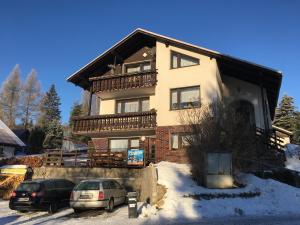 a large house with two cars parked in the snow at Penzion Janouškovi in Harrachov