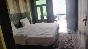a bedroom with a bed and a door with a window at Rupli homestay in Joshīmath