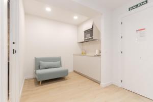 a living room with a chair and a kitchen at Pension Txapitela in Pamplona