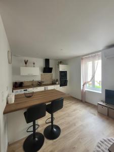a kitchen with a wooden counter and two bar stools at Appartement cosy in Commentry +5 photos