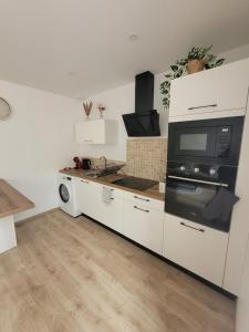 a kitchen with white cabinets and a microwave at Appartement cosy in Commentry