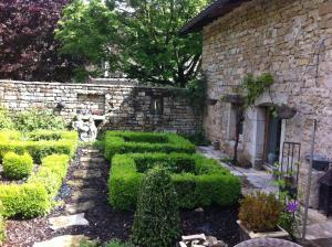 a garden with green bushes and a stone building at La Grange à Nicolas in Baume-les-Messieurs