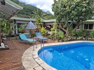 a swimming pool with two chairs and an umbrella at Chez Teivama in Haapiti