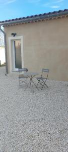 two chairs and a table in front of a building at studio chez amandine in Pernes-les-Fontaines