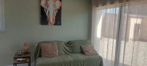 a living room with a green couch and a window at studio chez amandine in Pernes-les-Fontaines