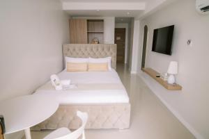 a bedroom with a large bed and a television at Palms La Union Beachfront Suites in San Juan
