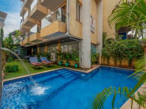 a swimming pool in front of a building at Trevon Hotels & Resorts Candolim Goa in Candolim
