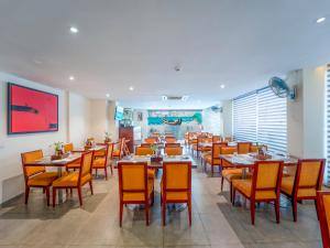 a dining room with tables and orange chairs at Trevon Hotels & Resorts Candolim Goa in Candolim