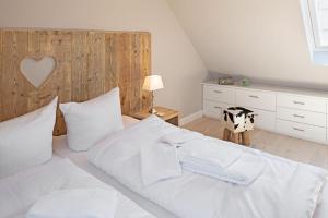 a bedroom with a large white bed with a wooden headboard at Sylter Perle in List
