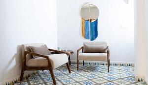 a living room with two chairs and a mirror at Dar Eddihi Essaouira in Essaouira
