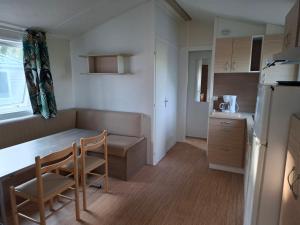 a kitchen with a table and chairs in a room at Camping Les Peupliers in Saint-Père-en-Retz