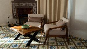 a living room with chairs and a coffee table and a fireplace at Dar Eddihi Essaouira in Essaouira