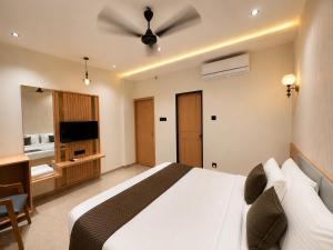 a bedroom with a white bed with a ceiling fan at Hotel Rushikesh inn Dwarka in Dwarka