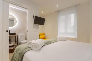 a white bedroom with a bed with towels on it at Pension Txapitela in Pamplona