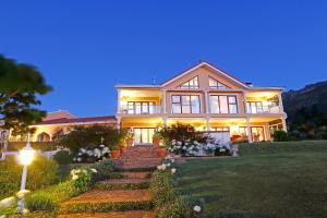 a large house with a staircase in front of it at Apricot Gardens Guesthouse in Gordonʼs Bay