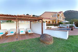 a house with a patio with chairs and a pool at Apricot Gardens Guesthouse in Gordonʼs Bay