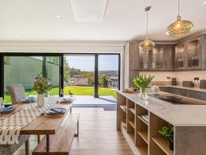 a kitchen with a wooden table and a large window at Brynor Lodge in Great Torrington
