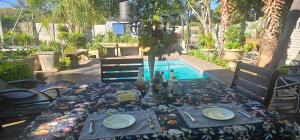 a table with plates and wine bottles on it next to a pool at Rose Stable Cottage in Pretoria +25 photos
