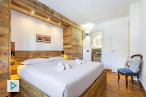 a bedroom with a large white bed with a blue chair at Hostdomus - Clotes Dream Suite in Sauze d'Oulx