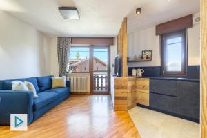 a living room with a blue couch and a kitchen at Hostdomus - Clotes Dream Suite in Sauze d'Oulx