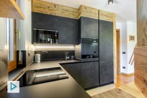 a kitchen with black cabinets and a stainless steel refrigerator at Hostdomus - Clotes Dream Suite in Sauze d'Oulx