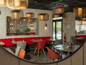 a restaurant with red chairs and tables in a mirror at ibis Orange Centre Echangeur A7 A9 in Orange