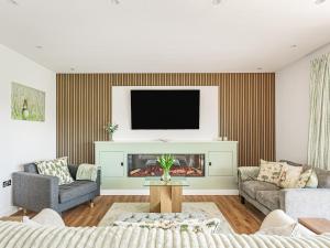 a living room with a tv above a fireplace at Brynor Lodge in Great Torrington