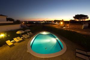 a swimming pool with chairs and umbrellas at night at Nuvolet Apartaments in Cala en Blanes