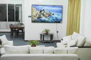 a living room with white couches and a tv on the wall at Nature Park villa in Arambegama