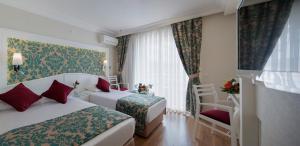 a hotel room with two beds and a window at Alaiye Kleopatra Hotel in Alanya +30 photos
