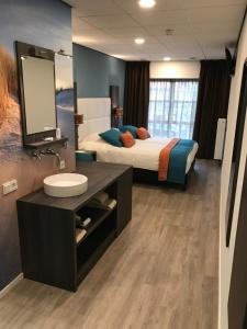 1 dormitorio con cama, lavabo y espejo en Rivers Hotel en Sluis