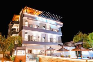 a large white building with umbrellas in front of it at Zogaj Hotel in Ksamil